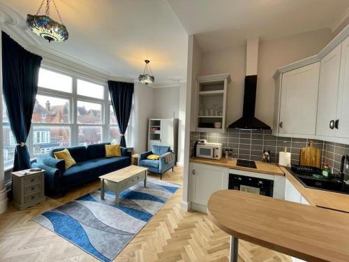 een keuken en een woonkamer met een blauwe bank bij Newly Refurbished 1 Bed Flat Southsea in Portsmouth