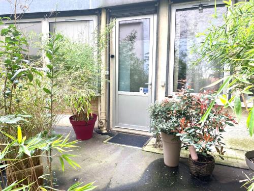 uma porta aberta com vasos de plantas em frente a uma casa em Maison de ville d'architecte parking gratuit em Paris