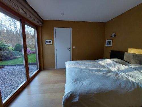 a bedroom with a bed and a large window at Chemin Babette in Stoumont