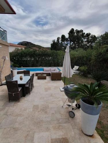 une terrasse avec une table, un parasol et une piscine dans l'établissement Maison à Saint-Florent avec piscine privée, à Oletta