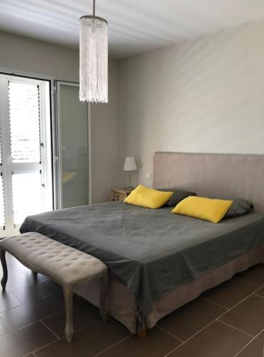 une chambre avec un grand lit avec des oreillers jaunes dans l'établissement Maison à Saint-Florent avec piscine privée, à Oletta