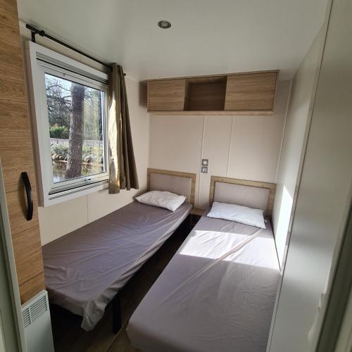 deux lits dans une petite pièce avec une fenêtre dans l'établissement Joli Bungalow Cap Ferret Camping les Viviers, à Lège-Cap-Ferret