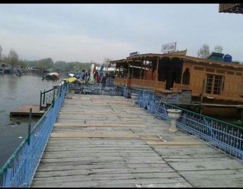 un quai avec un bâtiment à côté d'une masse d'eau dans l'établissement Aliflaila Laila Group of Houseboats , Srinagar, à Srinagar