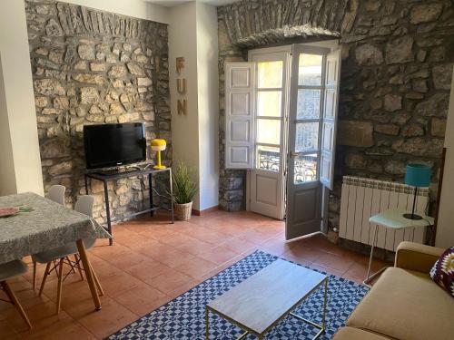 a living room with a tv and a stone wall at Apartamentos Hevia in Villaviciosa