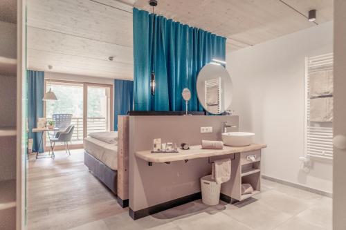 a bedroom with a bed and a sink and a mirror at Boutique Hotel LechZeit in Elmen