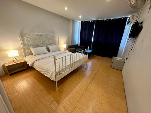 1 dormitorio con cama blanca y suelo de madera en The Cute Silom hostel, en Bangkok