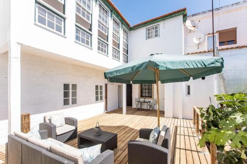 a patio with chairs and a green umbrella at Veloso Village Douro Valley by LovelyStay in Viseu