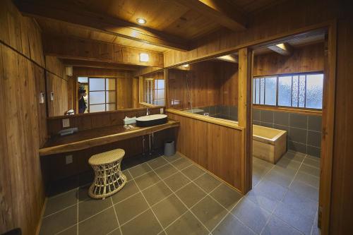 a bathroom with a sink and a tub and a stool at NIPPONIA 福住 宿場町 in Fukuzumi