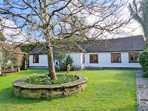 a tree in a flower bed in front of a house at Sussex Barns - Horsham in Horsham