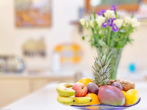 a plate of fruit on a table with a vase of flowers at Sussex Barns - Horsham in Horsham