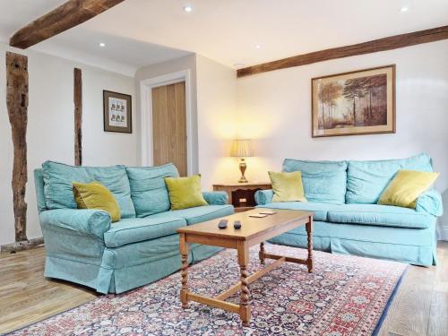 a living room with two blue couches and a table at Sussex Barns - Horsham in Horsham