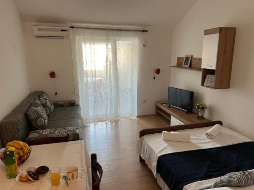 a room with a bed and a couch and a television at Apartments Mia Pag in Pag