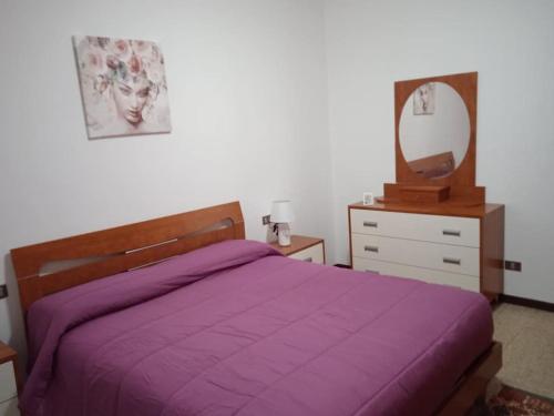 um quarto com uma cama roxa, uma cómoda e um espelho. em La casa di Lucia Appartamento em Novara