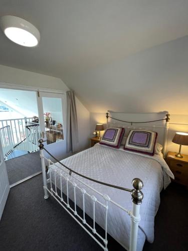 a bedroom with a white bed and a balcony at Bonnie Haven in Lochinver
