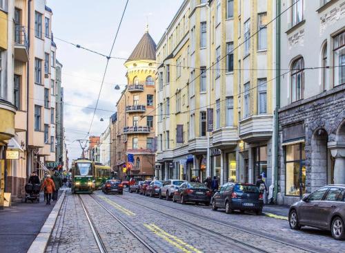 un tram su una strada cittadina con auto e palazzi di Art Nouveau - Jugend Talo in Helsinki Center Apartment a Helsinki