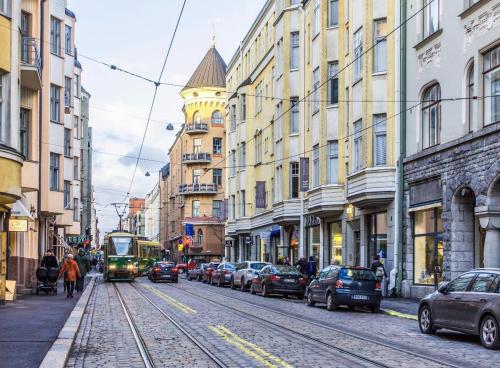 a tram on a city street with cars and buildings at Art Nouveau - Jugend Talo in Helsinki Center Apartment in Helsinki