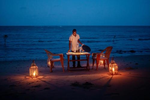 a man sitting at a table on the beach at night at Mwazaro Beach Lodge in Shimoni