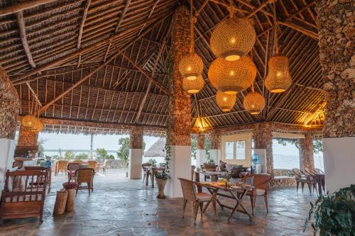 a restaurant with tables and chairs in a building at Mwazaro Beach Lodge in Shimoni