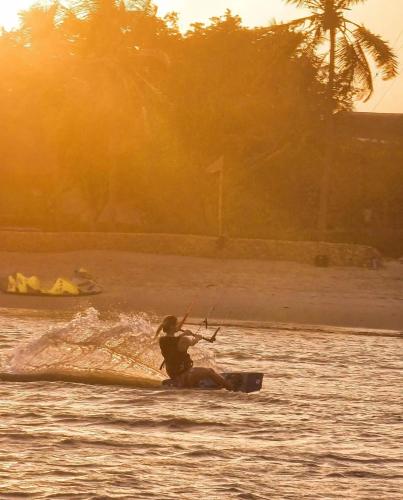a person kite surfing in the water at sunset at Mwazaro Beach Lodge in Shimoni