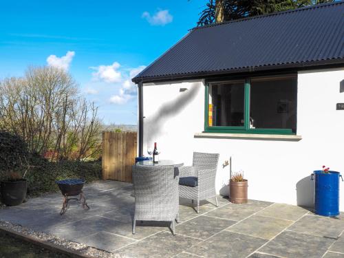 a patio with two chairs and a table and a building at Y Gegin Fach Cardigan in Rhos-hill