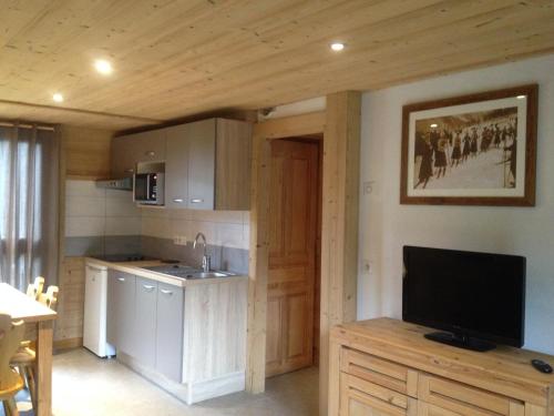 a kitchen with a television and a kitchen with a counter at Chalet Aravis in Le Grand-Bornand