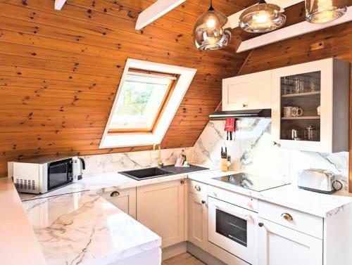 cocina con electrodomésticos blancos y pared de madera en Balor 1 - Hot Tub-Perth-Pets, en Perth