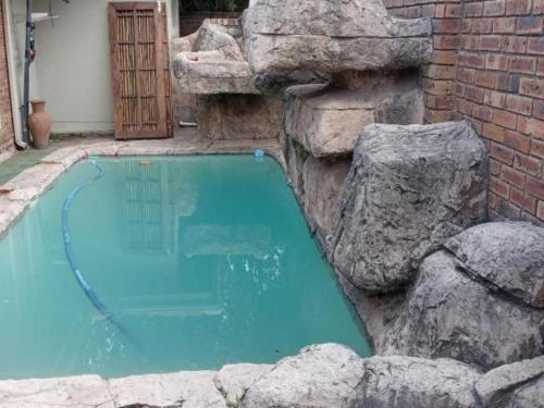a swimming pool with rocks next to a building at KWR B&B in Witbank