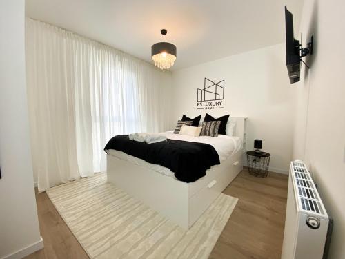 - une chambre blanche avec un lit et des oreillers en noir et blanc dans l'établissement The Modern Chic Haven, La Défense (16'), Parking, à Bezons