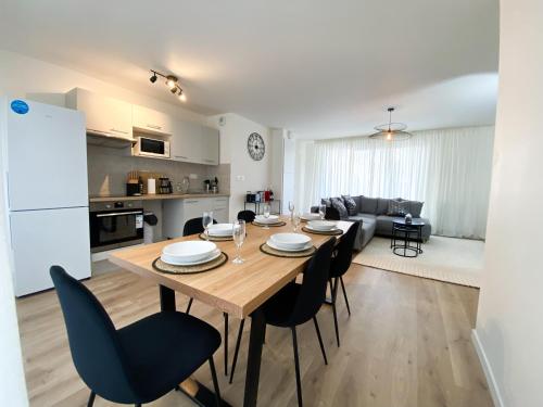 Il dispose d'une cuisine et d'un salon avec une table et des chaises en bois. dans l'établissement The Modern Chic Haven, La Défense (16'), Parking, à Bezons