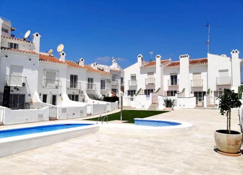 a courtyard of a large white building with a pool at CASITA BONITA NERJA in Nerja