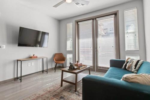 a living room with a blue couch and a flat screen tv at Cozysuites PHX RORO Gym Pool Pets Parking #12 in Phoenix