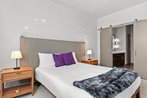 a bedroom with a large white bed with purple pillows at Cozysuites PHX RORO Gym Pool Pets Parking #12 in Phoenix