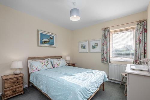 a bedroom with a bed and a desk and a window at 34 Llwyn Gwalch in Morfa Nefyn