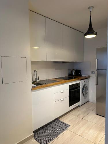 une cuisine avec des armoires blanches et une laveuse et une sécheuse dans l'établissement Joli appartement 49 m² proche centre Paris,, à Issy-les-Moulineaux