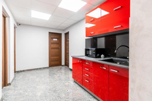 a kitchen with red cabinets and a sink at ReveliQa2 in Pobierowo