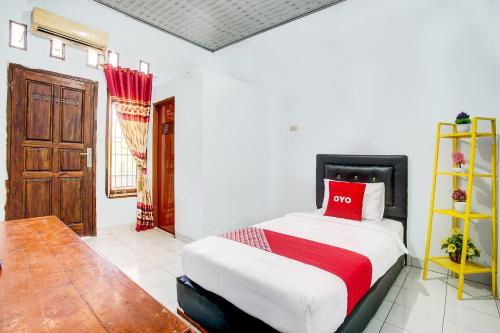 een slaapkamer met een bed met een rood kussen erop bij OYO 3994 Wisma Amalia in Bandar Lampung