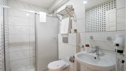 a white bathroom with a toilet and a sink at Kleopatra Ada Suites & Apartments in Alanya
