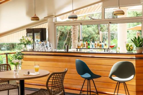a restaurant with a table and chairs and a bar at Résidence Valdys Thalasso & Spa - les Pins in Saint-Jean-de-Monts