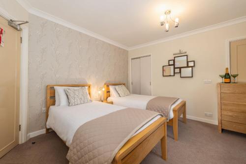 a bedroom with two beds and a dresser at Thornbank House Offering Breakfast and with the use of Free Local Health Club in Windermere