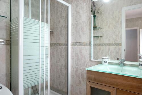 a bathroom with a sink and a glass shower at Casa El Muro in Vejer de la Frontera