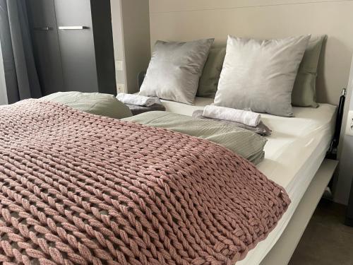 a bed with a red knitted blanket on it at Plaza Teatro & Piazzale Teatro in Rijeka