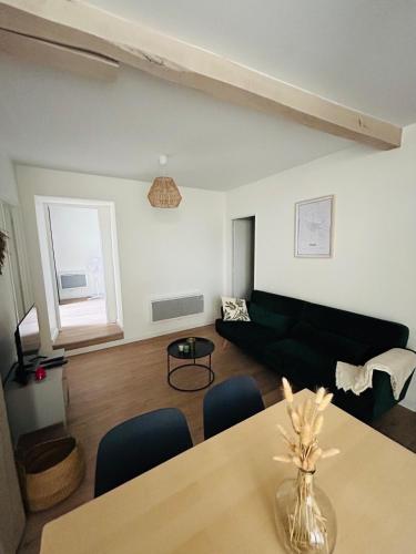- un salon avec une table et un canapé noir dans l'établissement Le patio : Appartement chic 3 chambres au cœur de Pau, à Pau