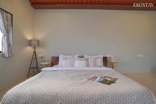a bedroom with a bed with a book on it at Ekostay Gold Palm Estate I Cricket Turf I Rain Dance I 2 Acre Property in Karjat