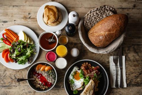uma mesa com pratos de alimentos para pequeno-almoço e pão em Sundvolden Hotel em Sundvollen