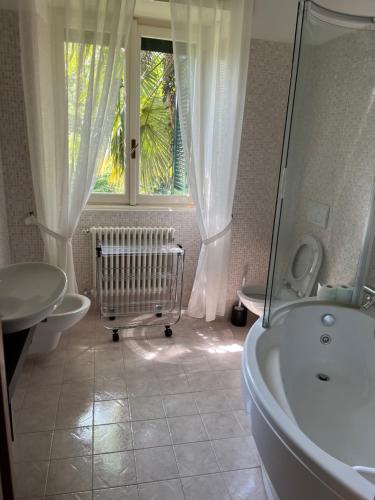 een badkamer met een bad, een wastafel en een raam bij Villa Moia in Varese