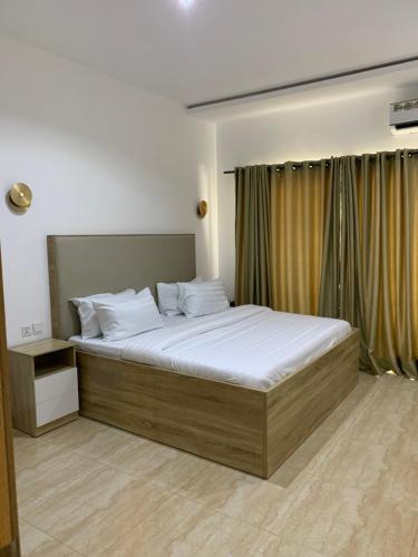 um quarto com uma cama grande e lençóis brancos em Greywood Hotel and Apartments em Ikeja