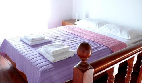 a bed with a purple blanket and towels on it at Villa Rosa in Kattavía