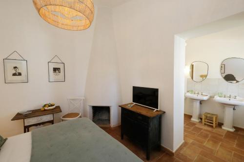 a bedroom with a bed and two sinks and a television at Quinta Baltazar Casa particular in Vila Nova de Cacela