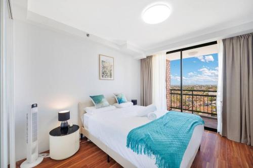 a white bedroom with a bed and a large window at Sky-view 2B2B1G in Hurstville -1 min to Westfield in Sydney