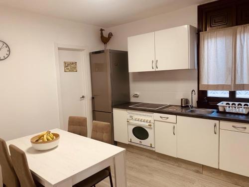 a kitchen with white cabinets and a table with a bowl of bananas at Casa Susanna Apartment Costa del Silencio in Costa Del Silencio